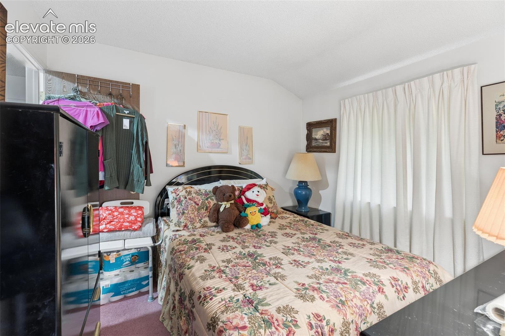 Bedroom featuring a vaulted ceiling and floor-to-ceiling curtain window coverings