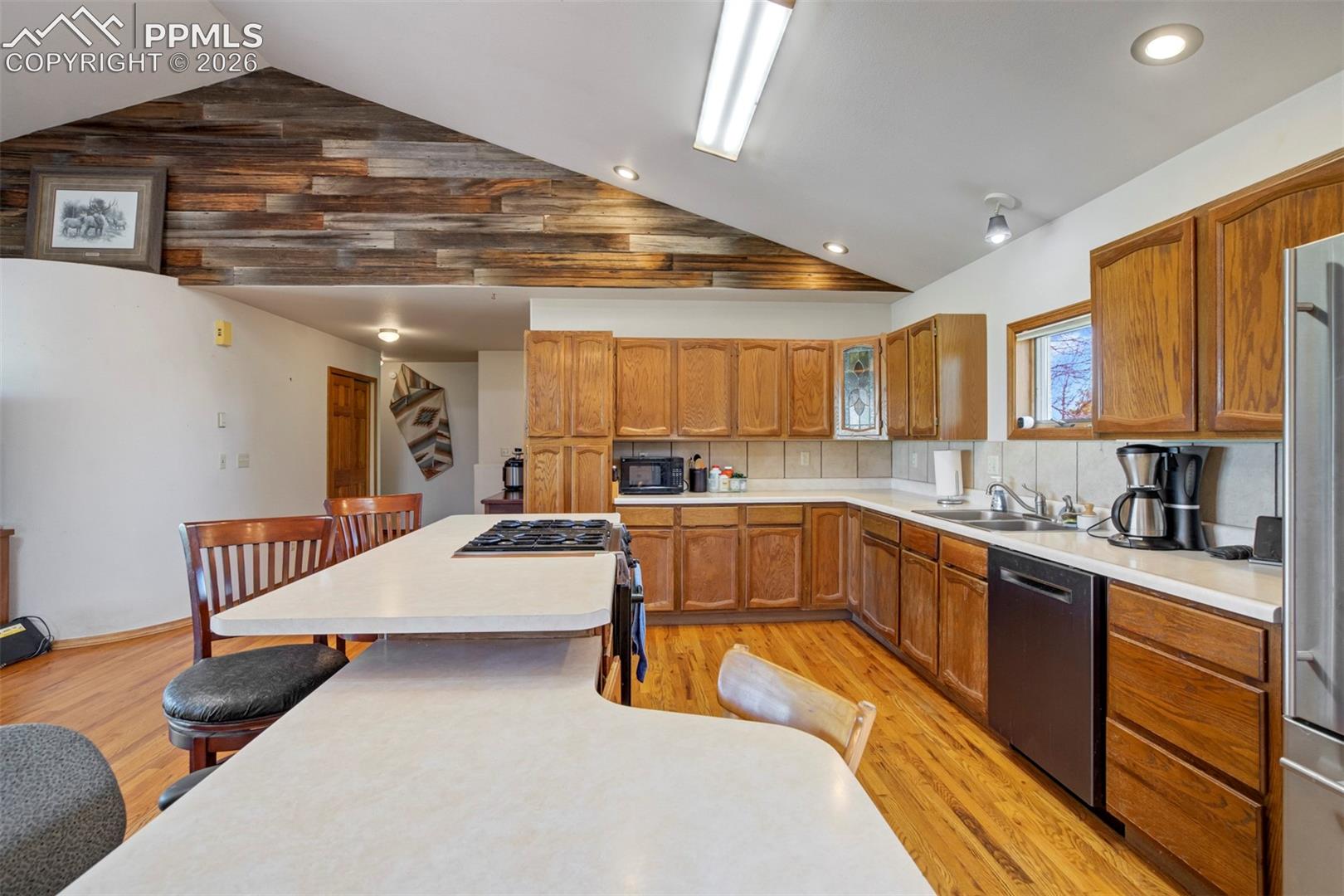 Spacious kitchen featuring wood-finish flooring, a large island with an integrated cooktop, and abundant wood cabinetry