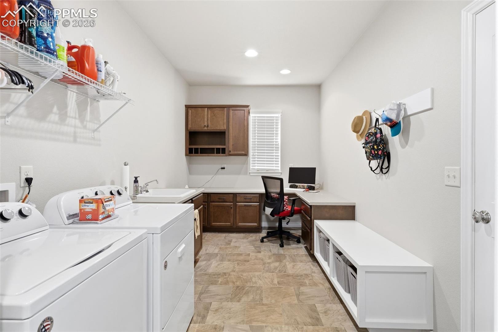 Expansive mud room with boot bench and desk area and utility sink