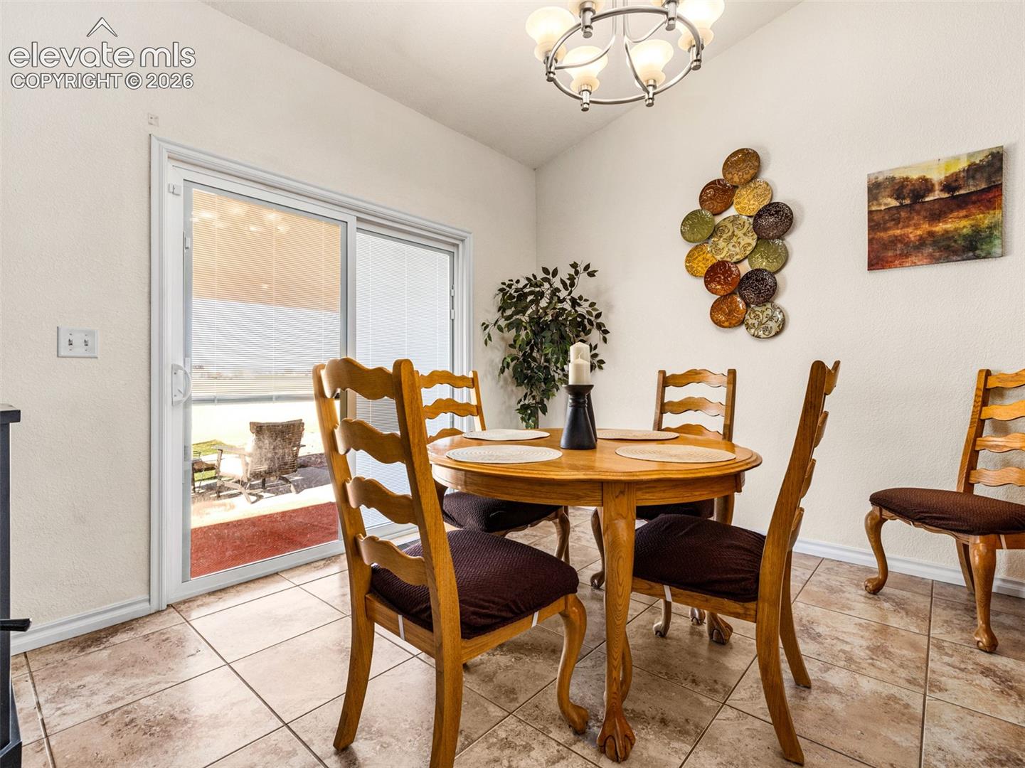 Sliding glass door, tiled flooring, overhead light fixture, light-toned walls, and outdoor patio area