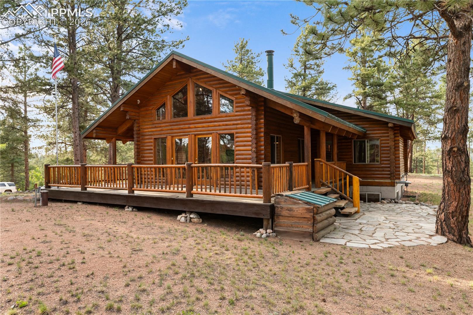 View of front facade featuring log exterior, a wooden deck, and french doors