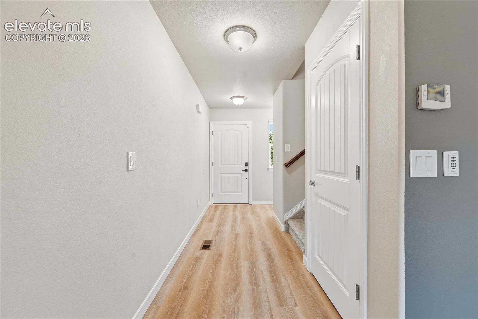 Entryway featuring wood-finish flooring, light neutral wall tones, and white trim