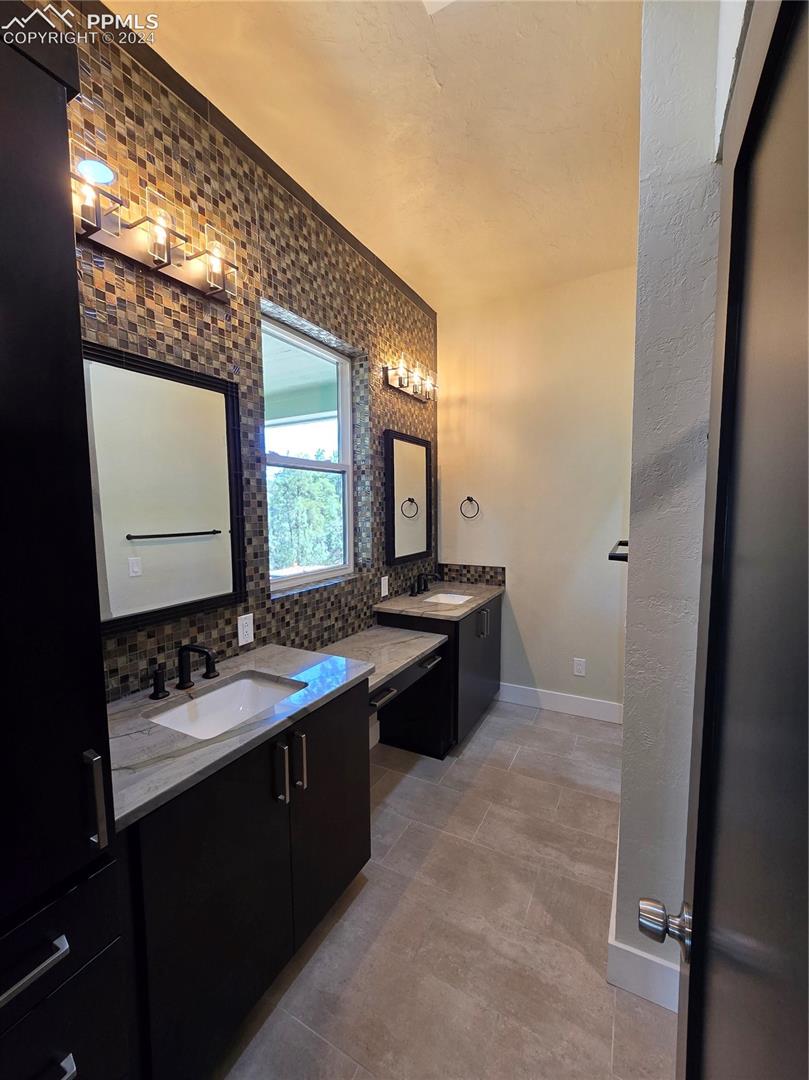 Bathroom with ornamental molding, vanity, and tasteful backsplash
