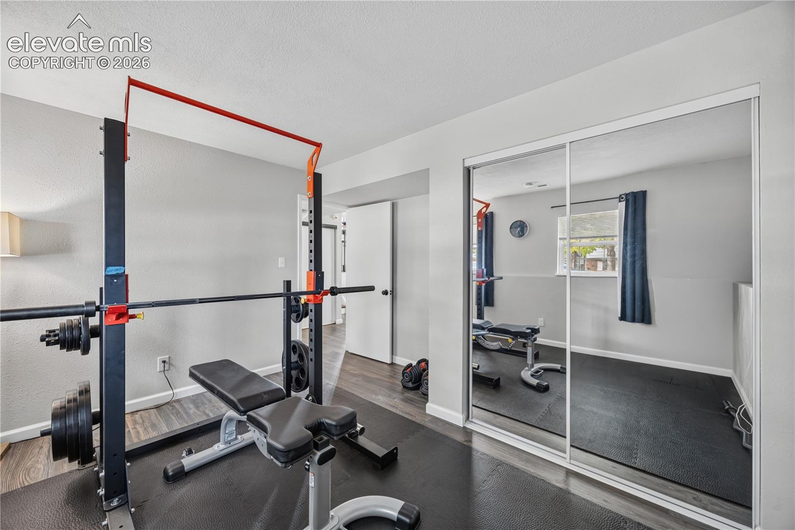 Interior space featuring wood-finish flooring, neutral wall paint, and double sliding mirrored closet doors