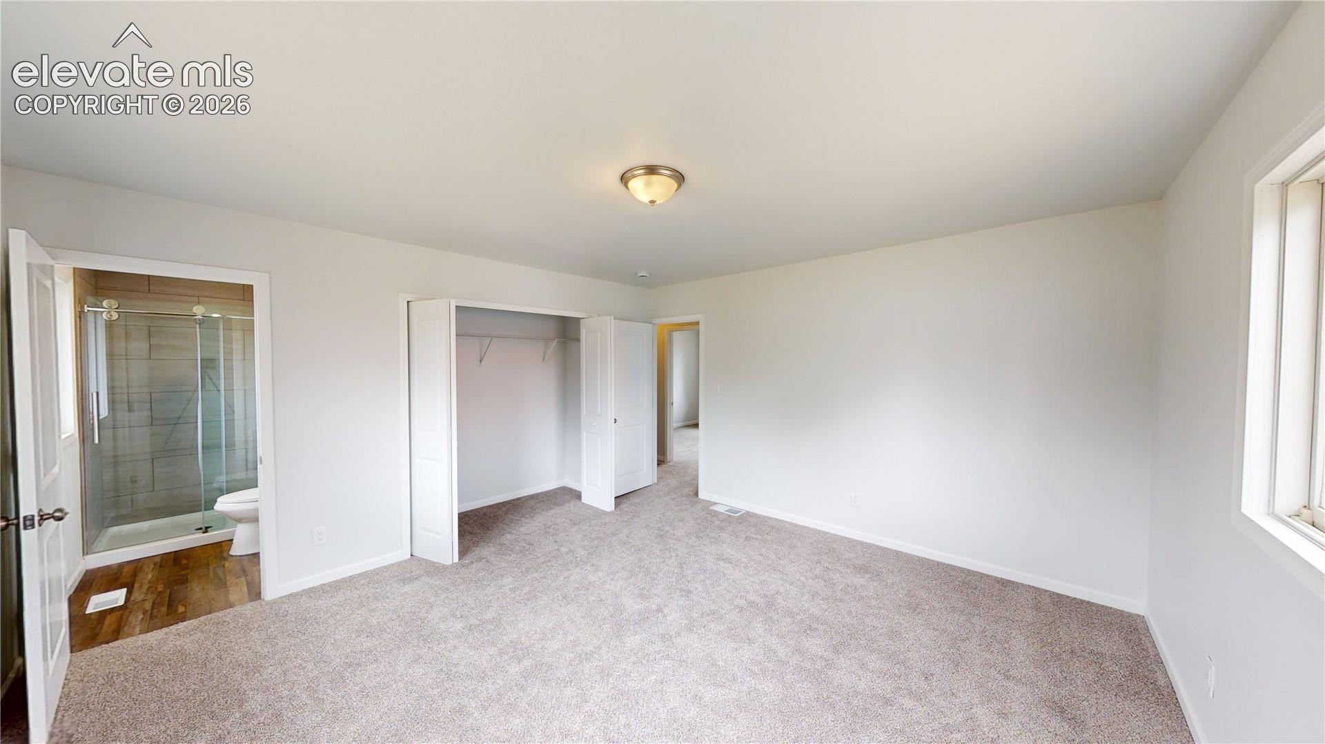 Carpeted flooring with an overhead ceiling light fixture, a window, and a built-in closet