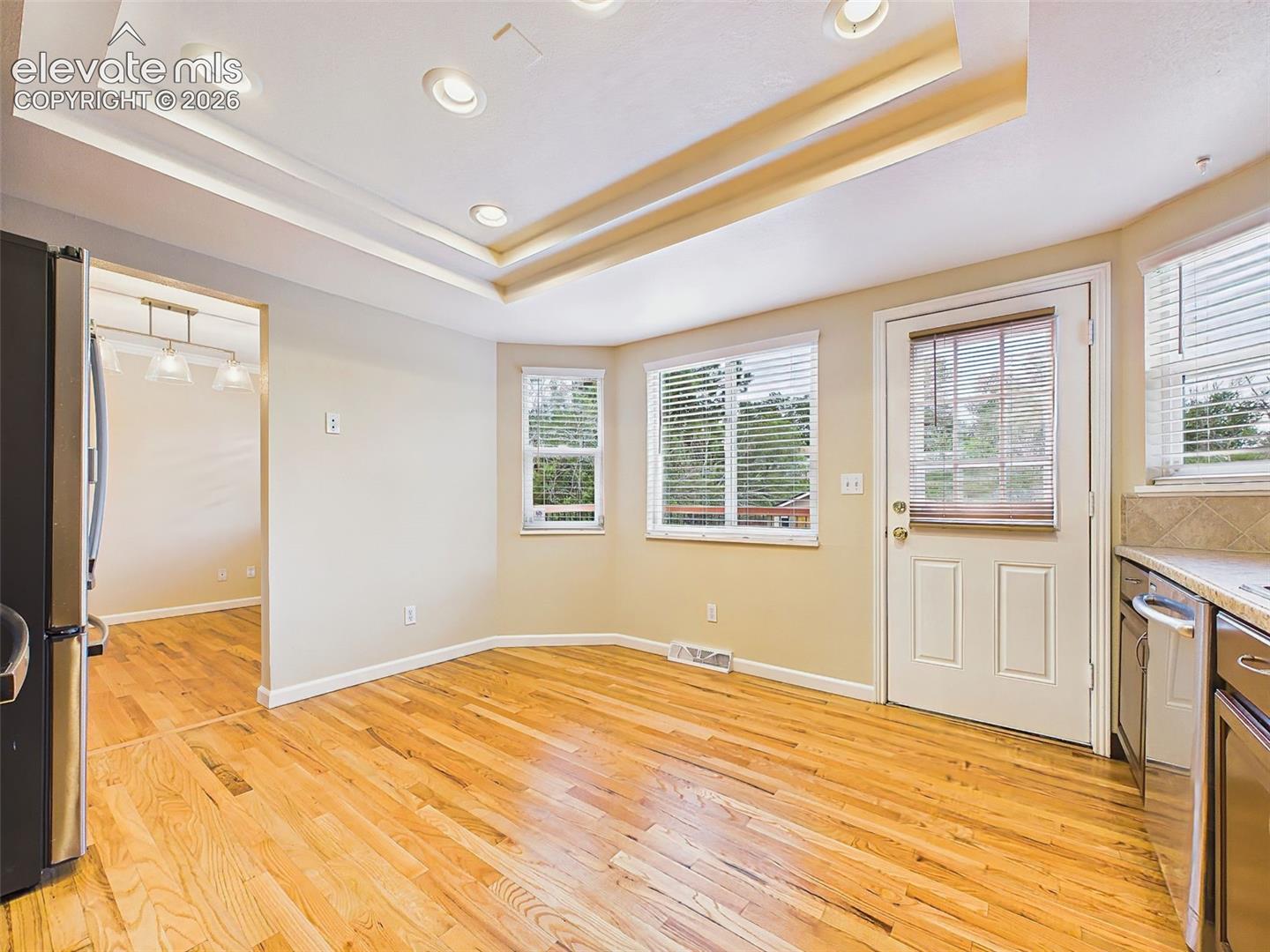 The open kitchen features hardwood flooring, rich wood cabinetry, stainless steel appliances, and convenient access to the outdoor entertaining area.