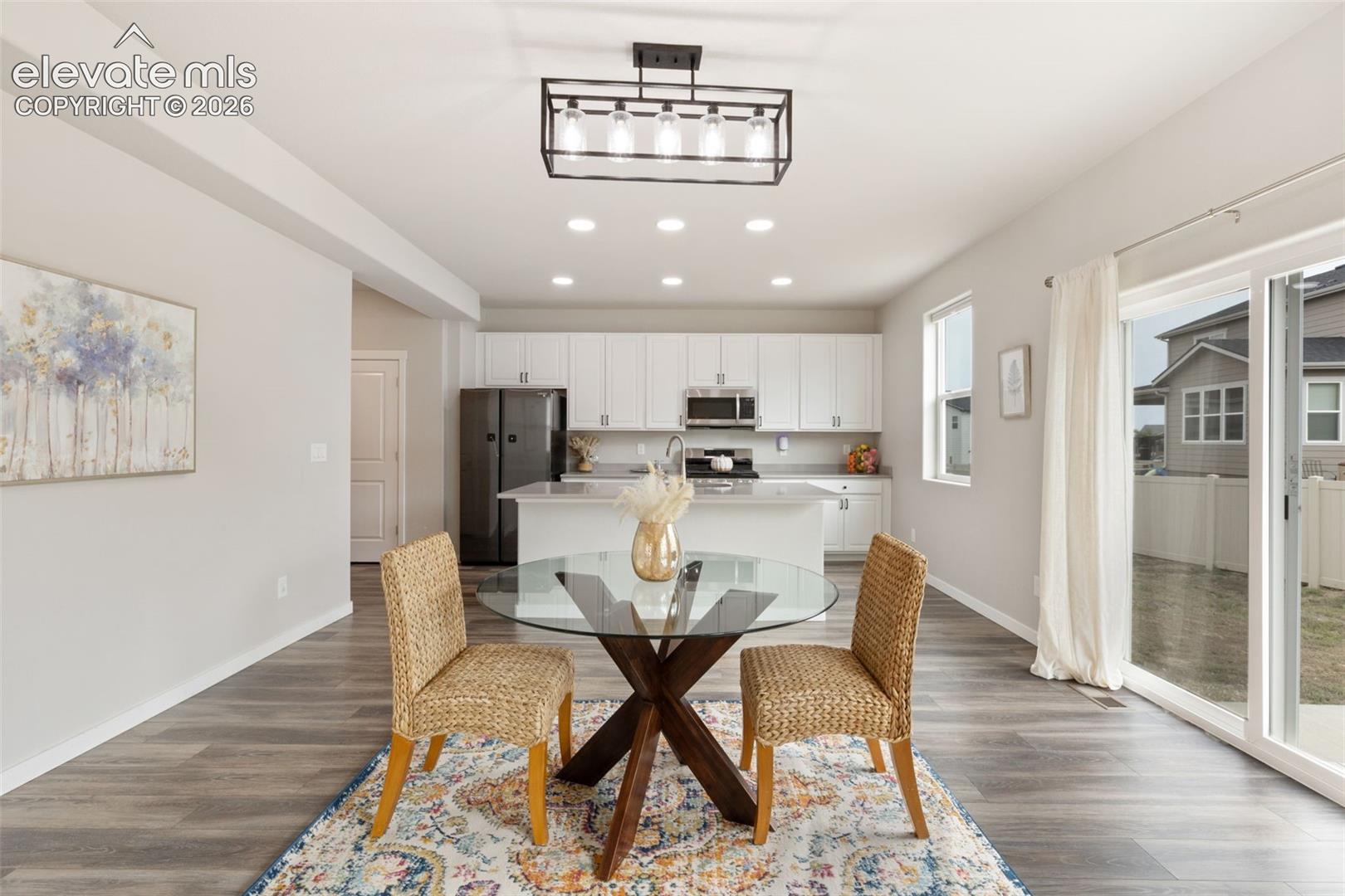 Open-concept kitchen and dining area featuring wood-finish flooring and recessed lighting