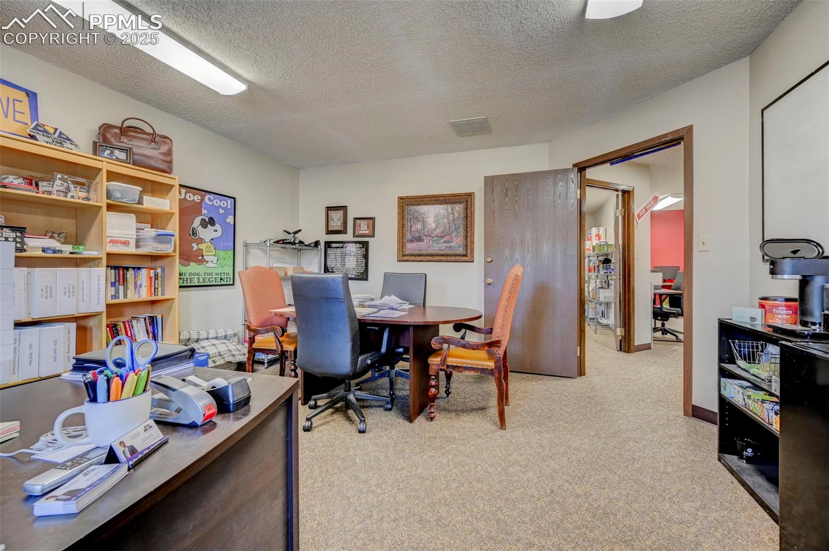 Home office with light colored carpet and a textured ceiling