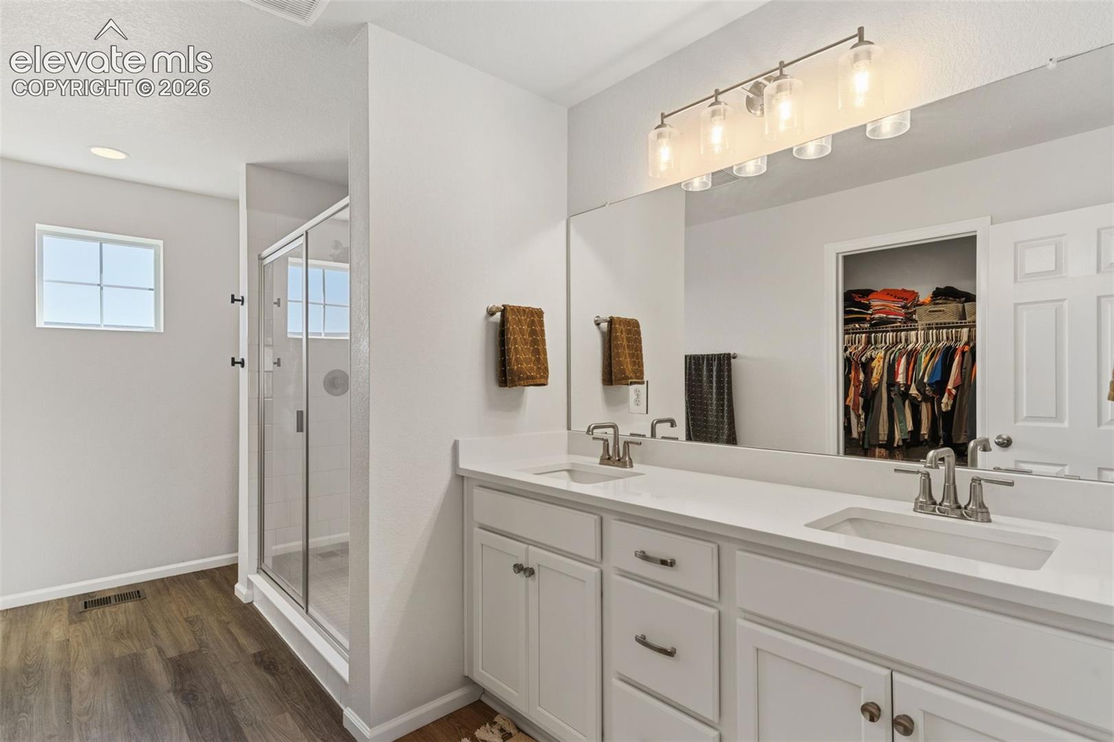 Spacious bathroom featuring a dual vanity with white cabinetry and an expansive mirror