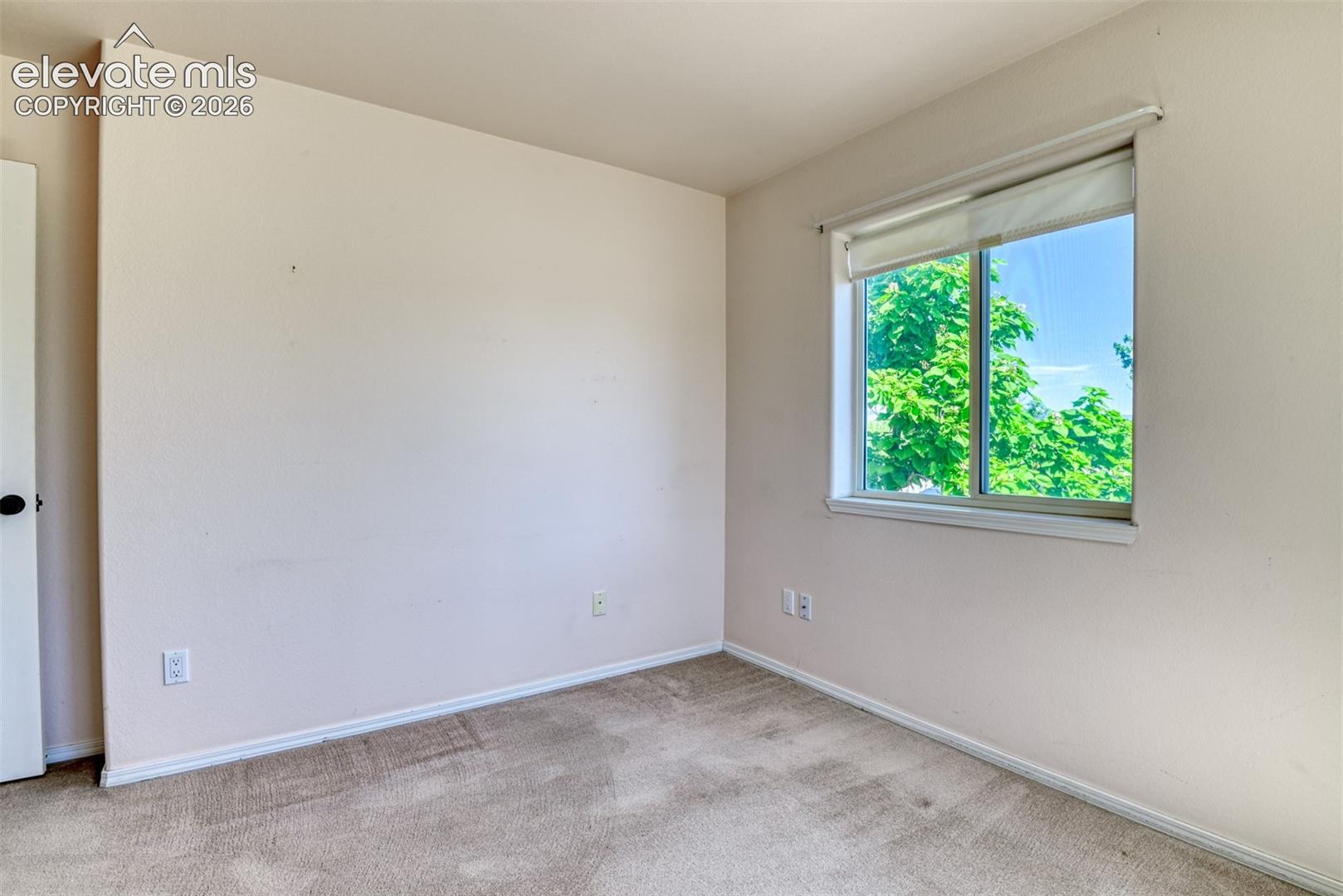 Neutral-toned interior space featuring wall-to-wall carpeting and a dual-pane sliding window