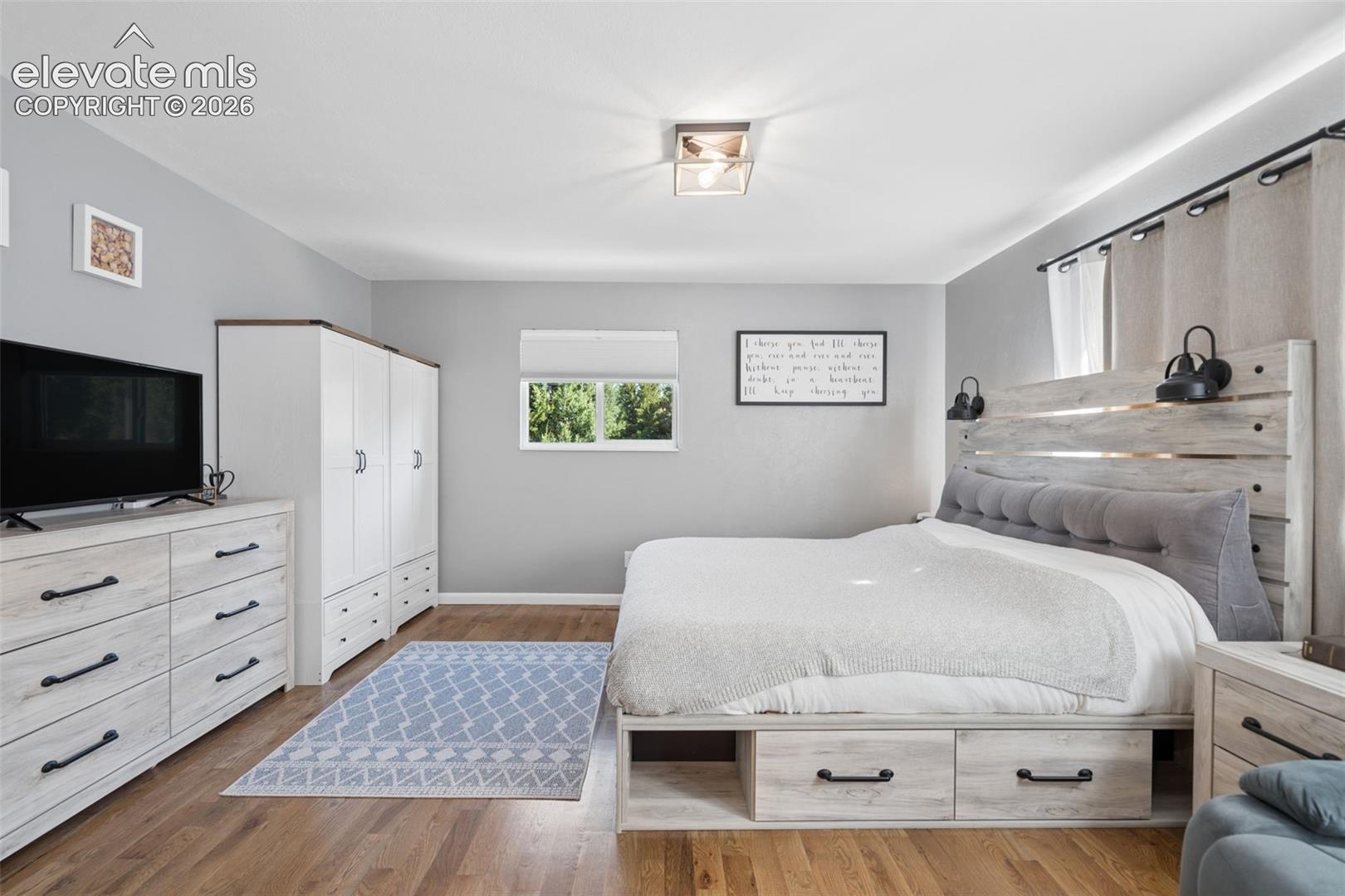 Wood-finish flooring, neutral wall tones, window with exterior exposure, and flush-mount ceiling lighting