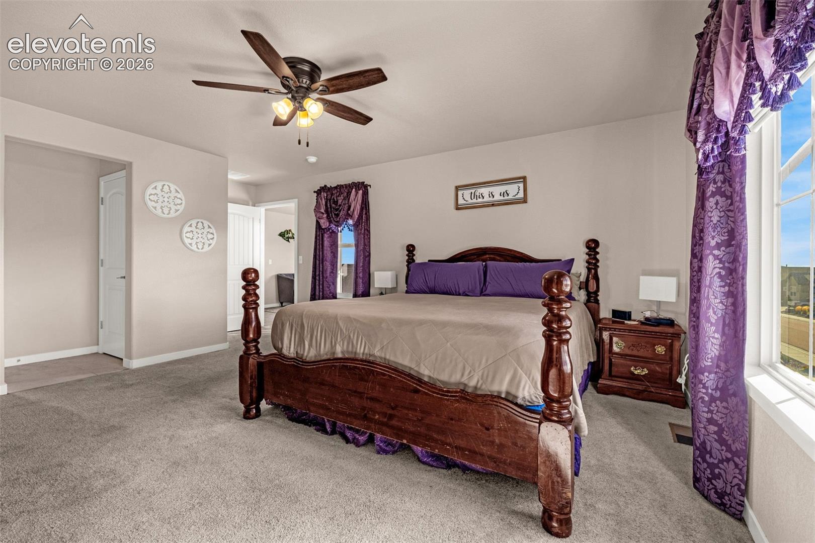 Neutral wall tones, wall-to-wall carpeting, ceiling fan with integrated lighting, and multi-pane windows
