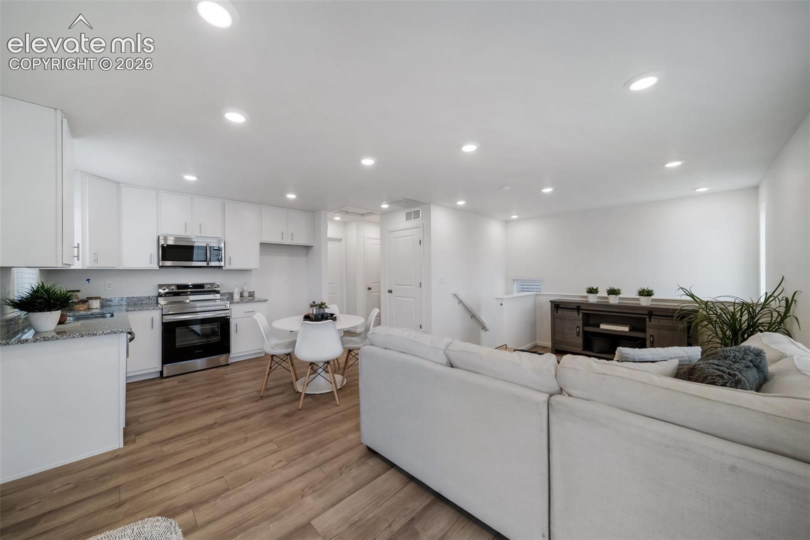 Stainless steel kitchen appliances, white cabinetry, granite countertops, wood-finish flooring, and recessed lighting
*photos of a model home*