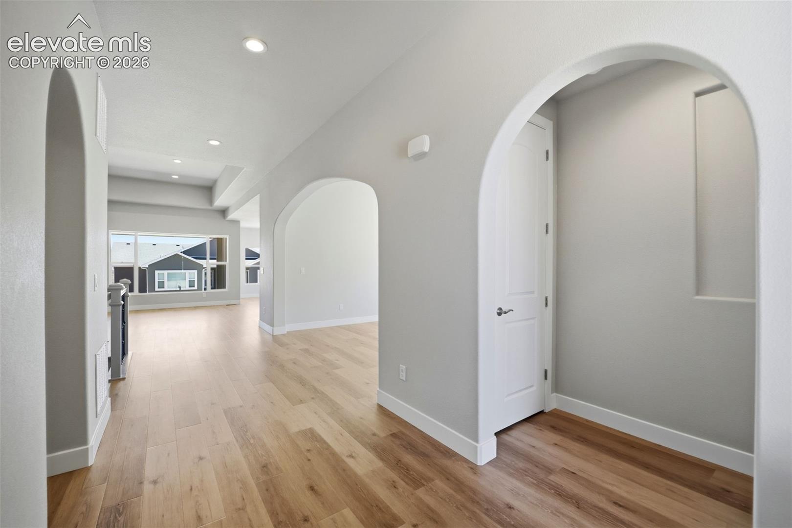 Interior featuring arched doorways, wood-finish flooring, recessed lighting, and a recessed wall niche