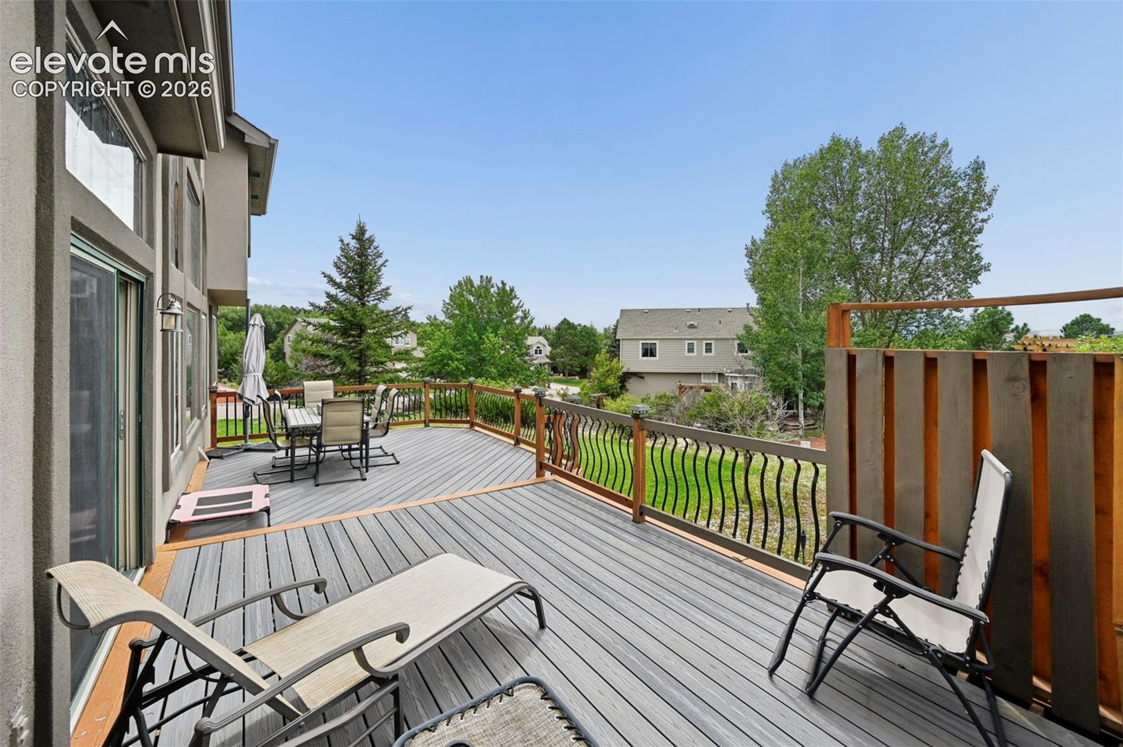Expansive elevated deck with composite decking, wrought iron railing, and a privacy screen