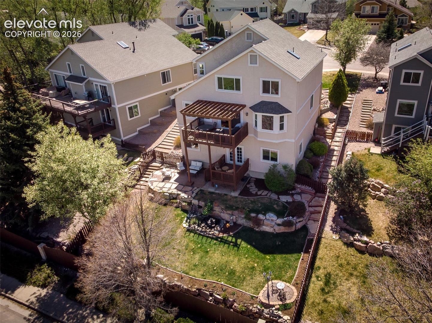 View of back yard with terraced landscaping and mature trees