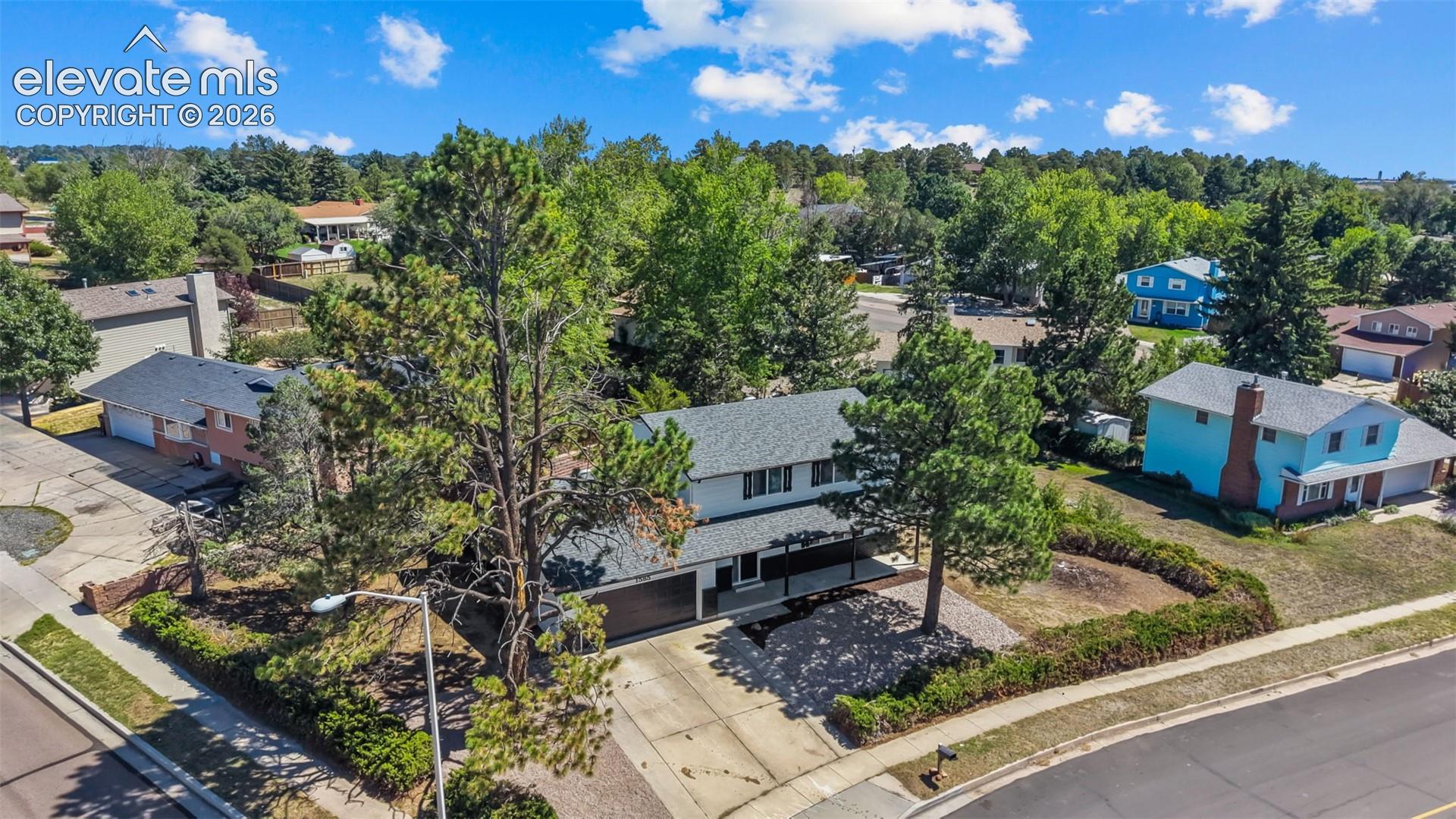 Two-story exterior with a two-car garage, mature landscaping, and an asphalt driveway