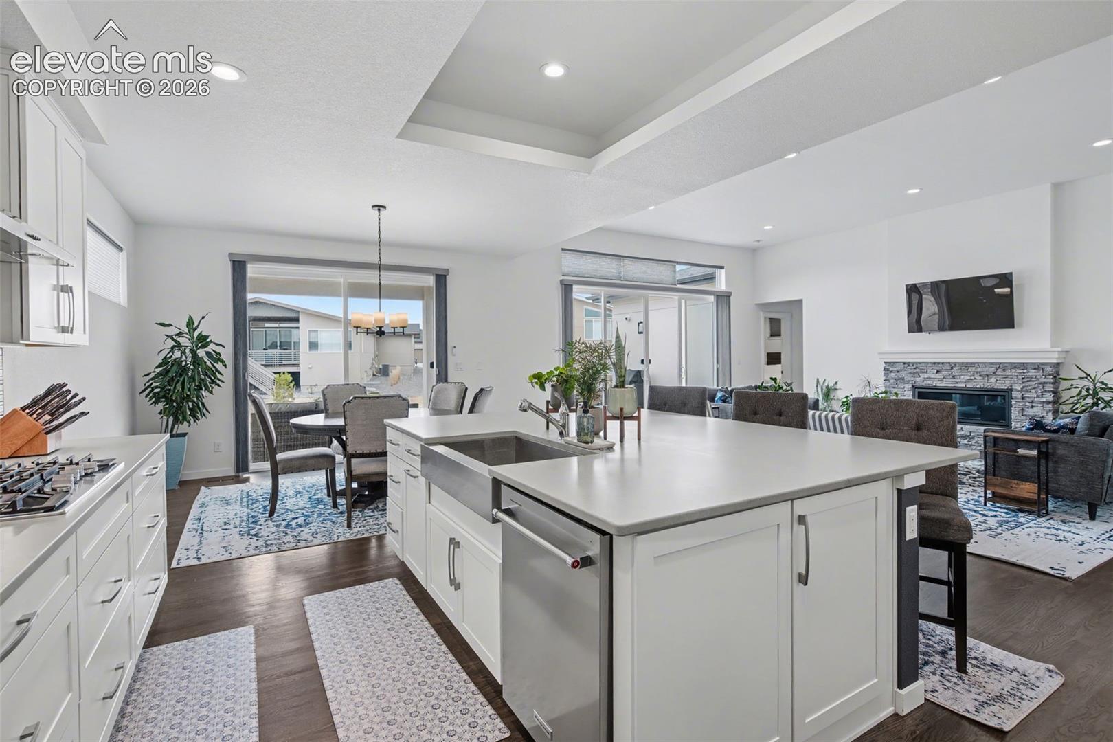 Kitchen featuring white cabinets, open floor plan, a kitchen bar, a kitchen island with sink, and stainless steel appliances