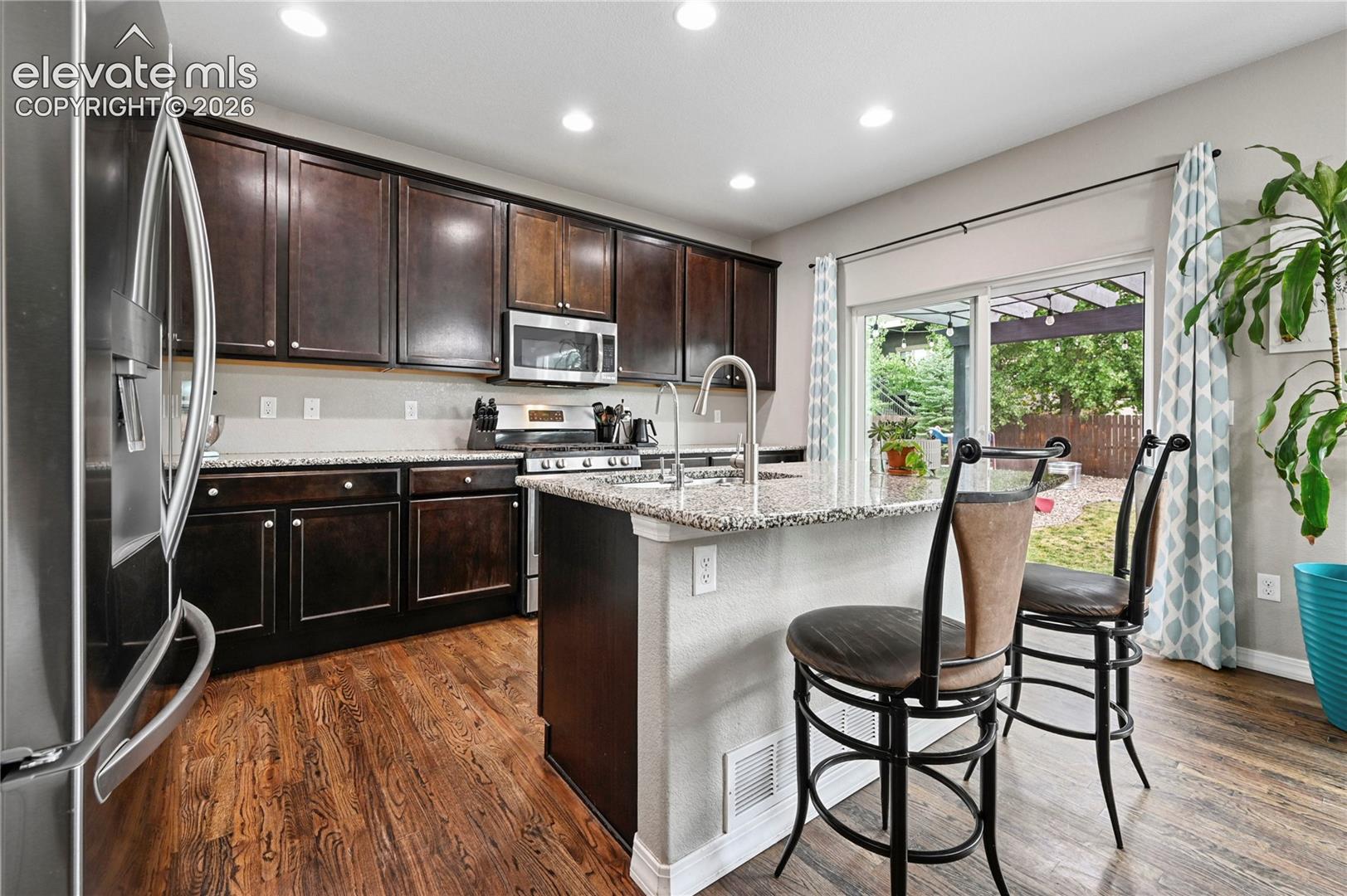 The kitchen is upgraded to a gas range, plus 42" upper cabinetry, granite counters, and a sliding glass door for easy indoor/outdoor life.