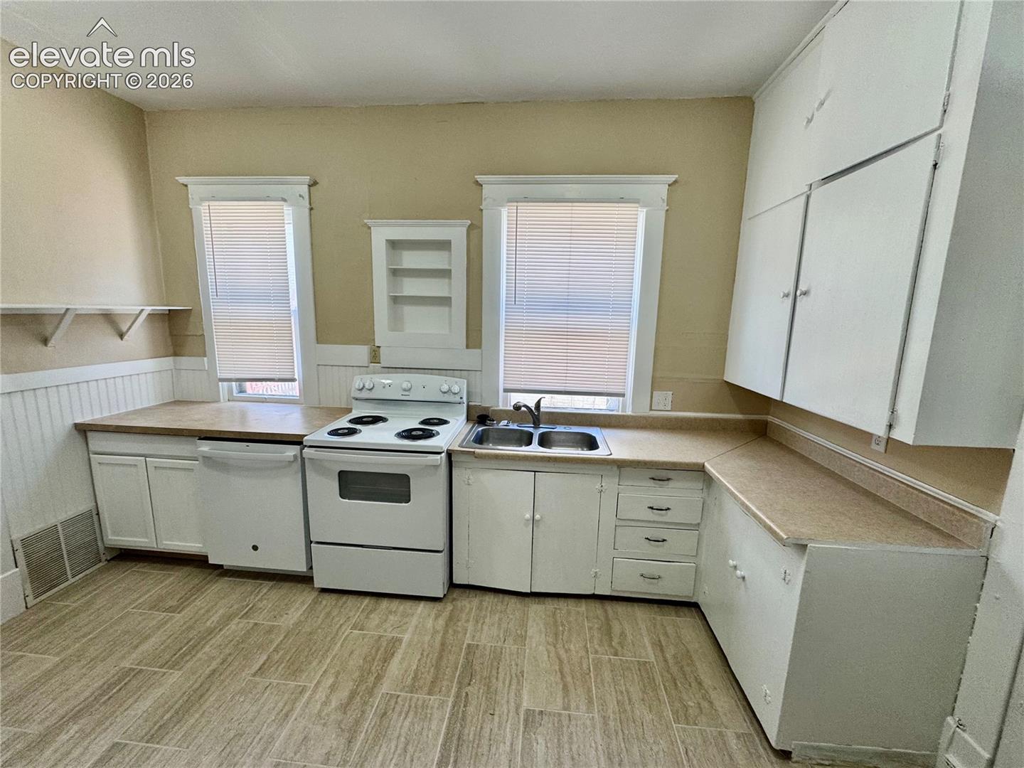Kitchen featuring wood-finish flooring, white cabinetry, integrated dishwasher, and a double basin sink