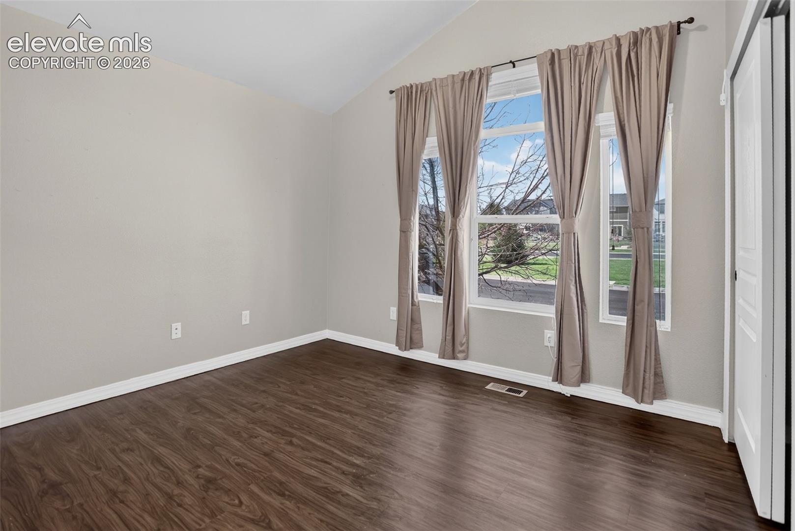 Vaulted ceiling, durable wood-finish flooring, built-in shelving, expansive windows, and a built-in desk with drawer storage