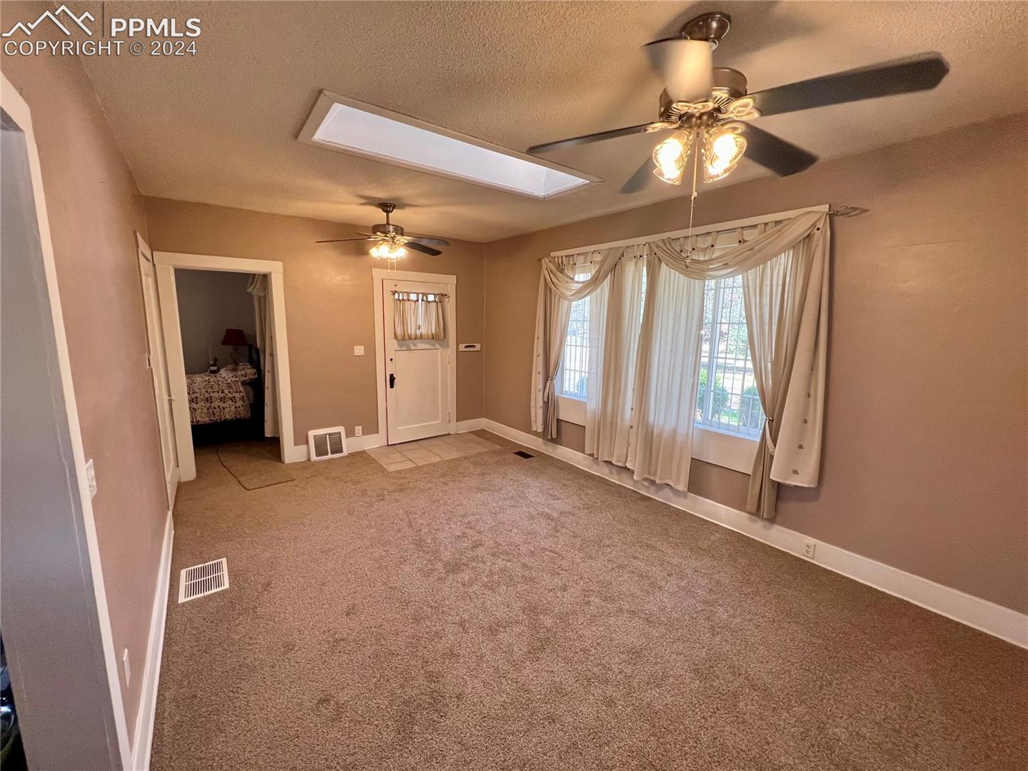 Carpeted empty room featuring a textured ceiling and ceiling fan