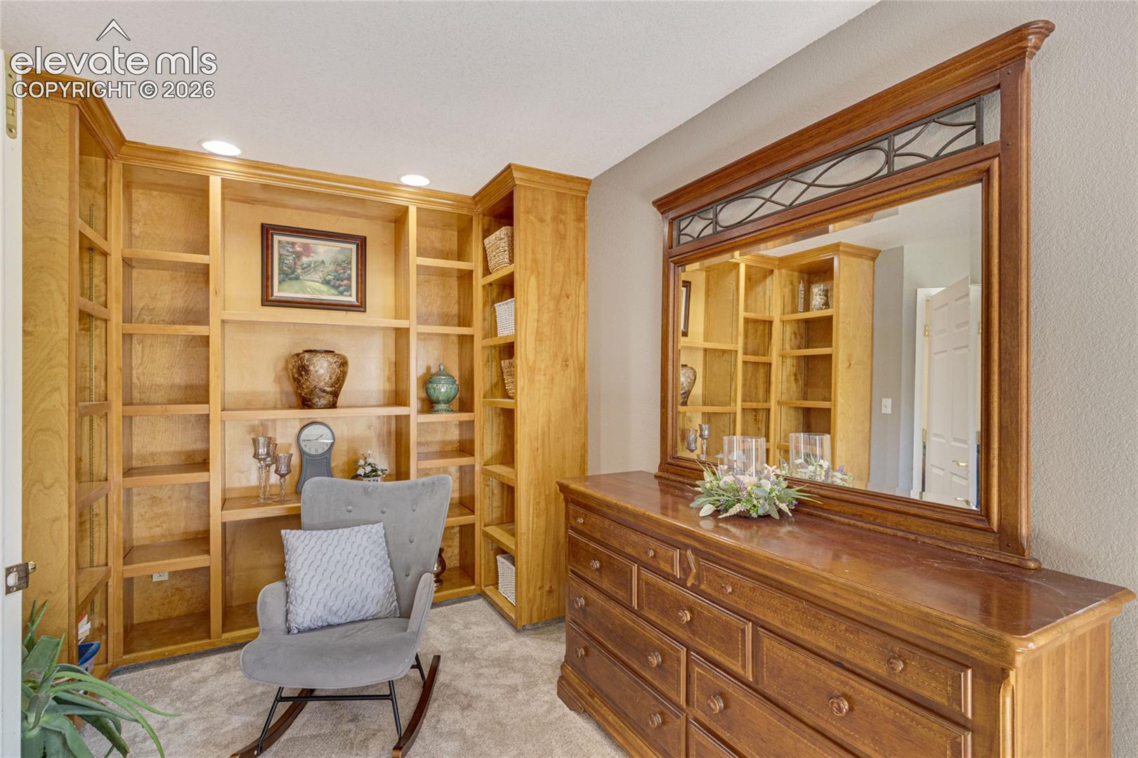 Custom floor-to-ceiling wooden built-in shelving featuring recessed lighting
