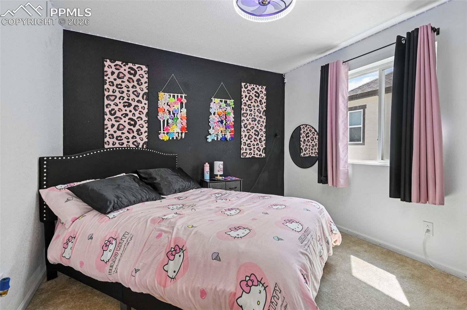 Neutral colored carpeted flooring, a ceiling-mounted light fixture, and a window with dark and pink curtains
