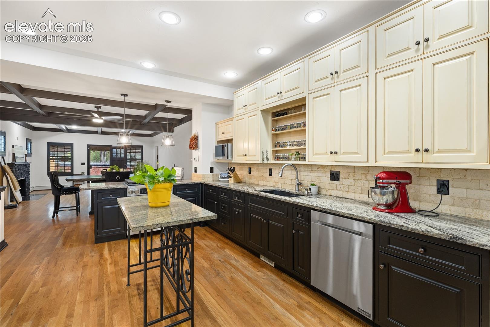 Gourmet kitchen featuring wood-finish flooring, two-tone cabinetry with black base cabinets and cream upper cabinets, stone countertops, a stainless steel dishwasher, and recessed lighting