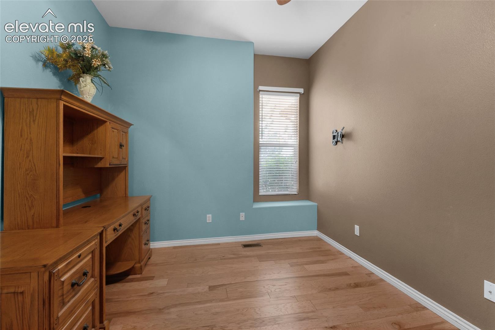 Room featuring wood-finish flooring, built-in oak cabinetry, and an integrated window seat