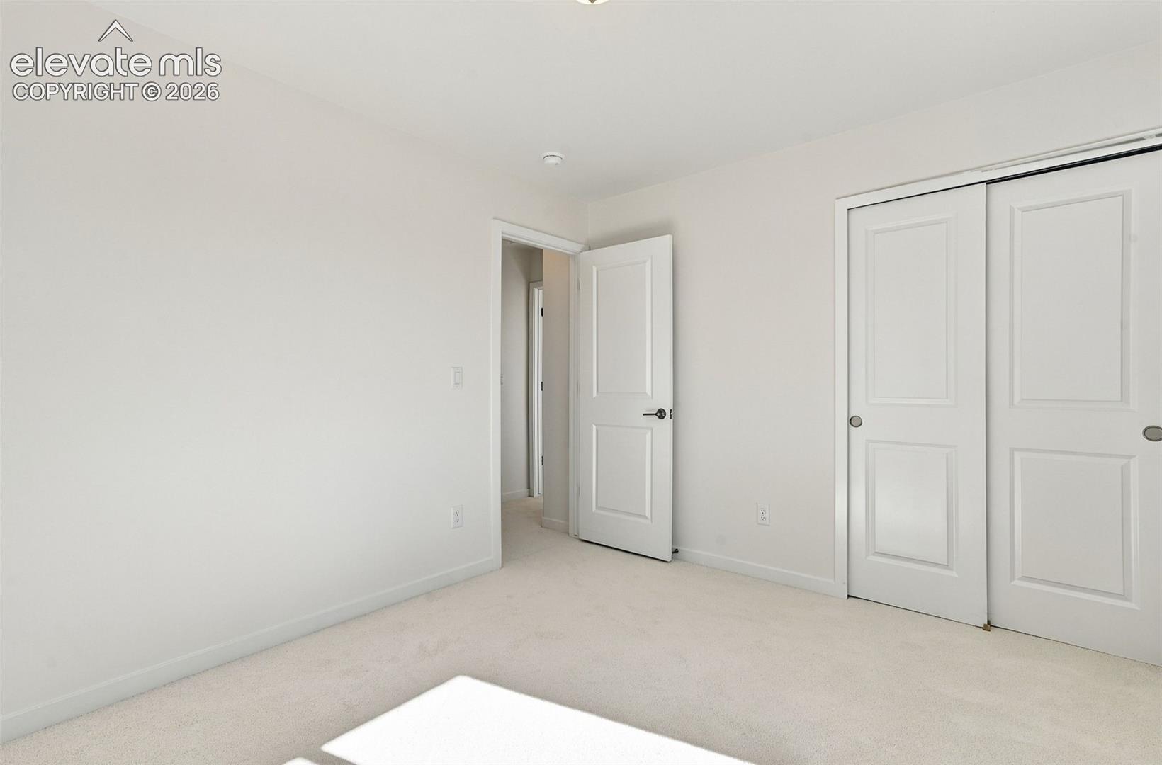 Light-colored carpeting, white walls, white paneled doors, and a recessed ceiling light
