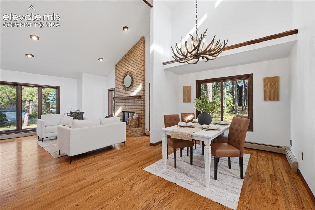 Vaulted ceilings, exposed brick fireplace, recessed lighting, wood-finish flooring, and expansive windows