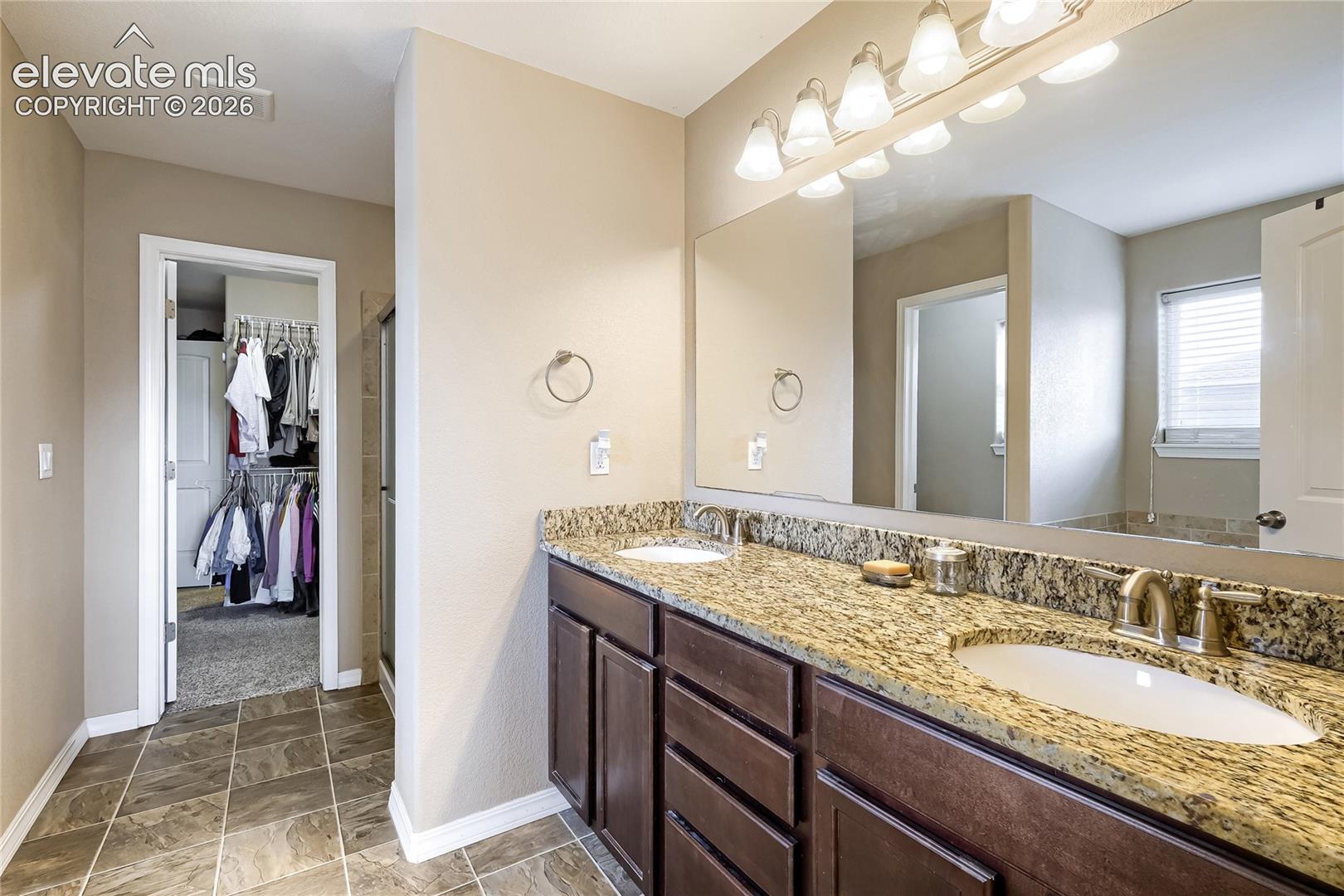 Primary bathroom adjoins with this double vanity featuring granite countertops and undermount sinks