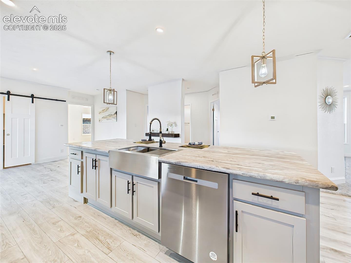 Stainless steel dishwasher in the island and pendent lights for a clean, upscale look.