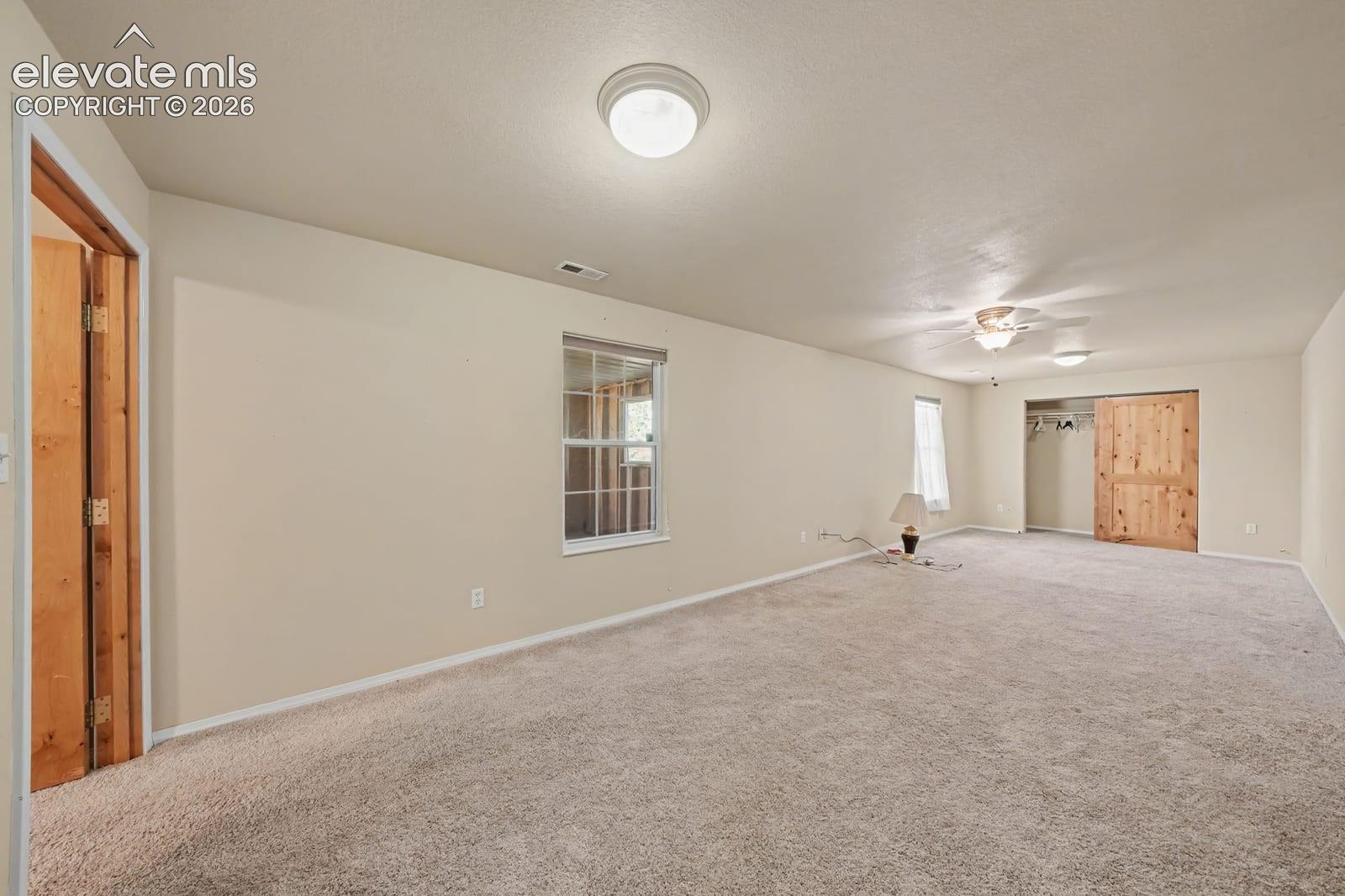 Interior space featuring wall-to-wall carpeting, dual-pane windows, ceiling-mounted lighting, and natural wood doors