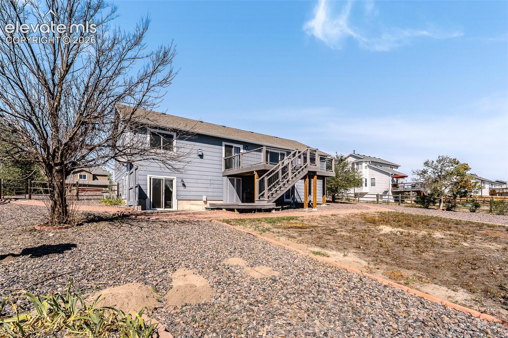 Rear view of home and fenced backyard.