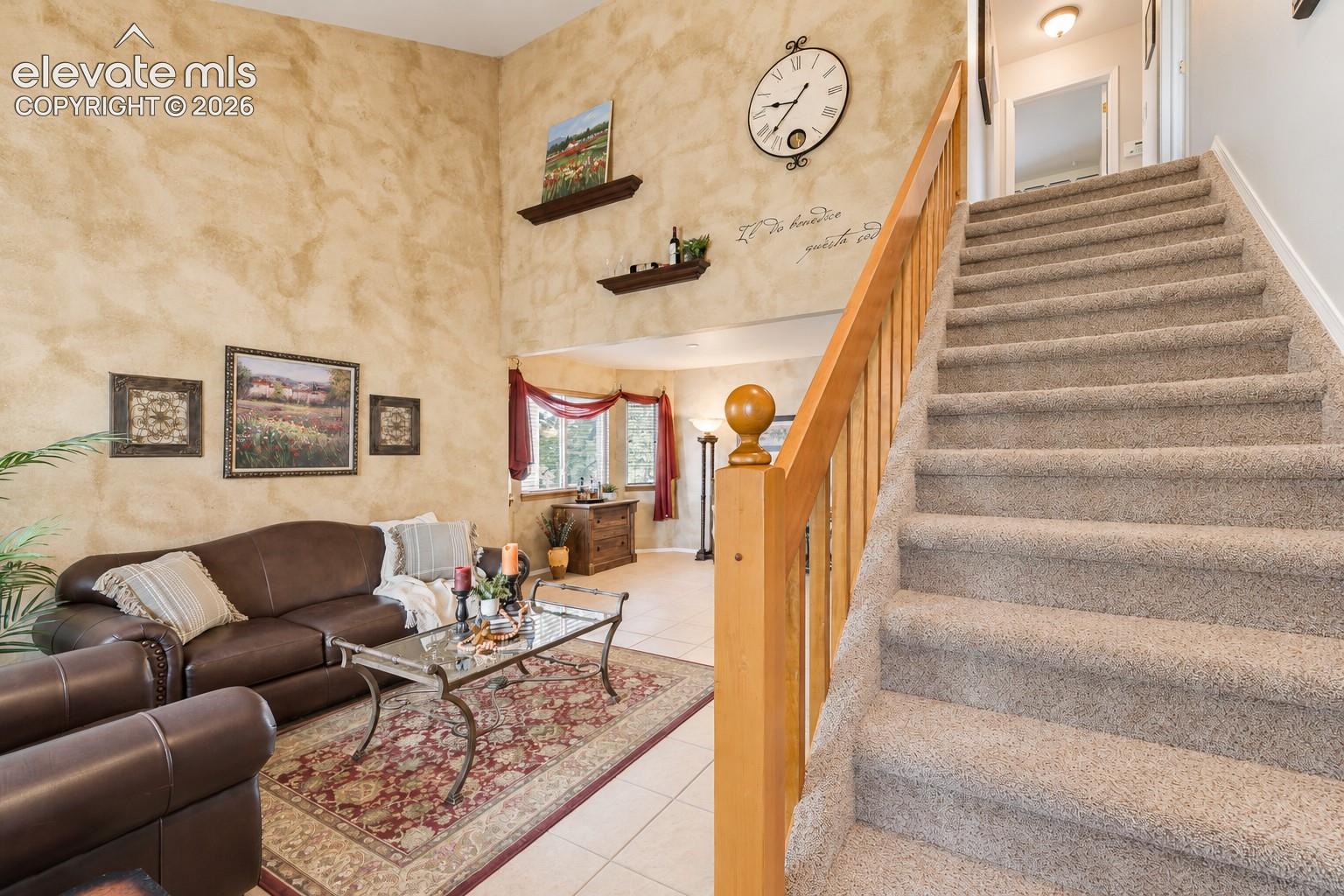 High ceilings, an open staircase, and warm architectural details enhance this spacious main living area.