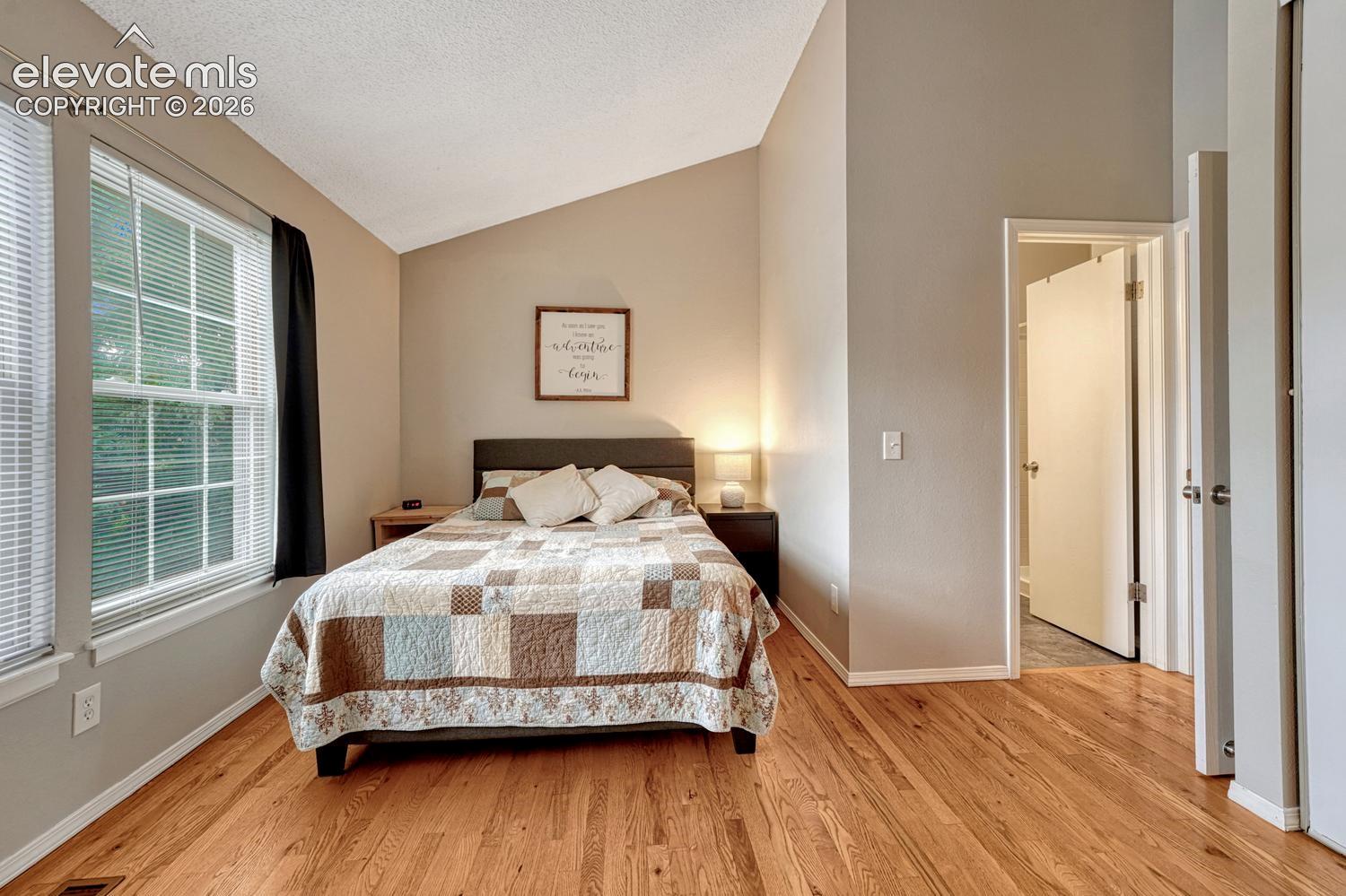 Second bedroom also features hardwood floor, vaulted ceiling, and attached bathroom