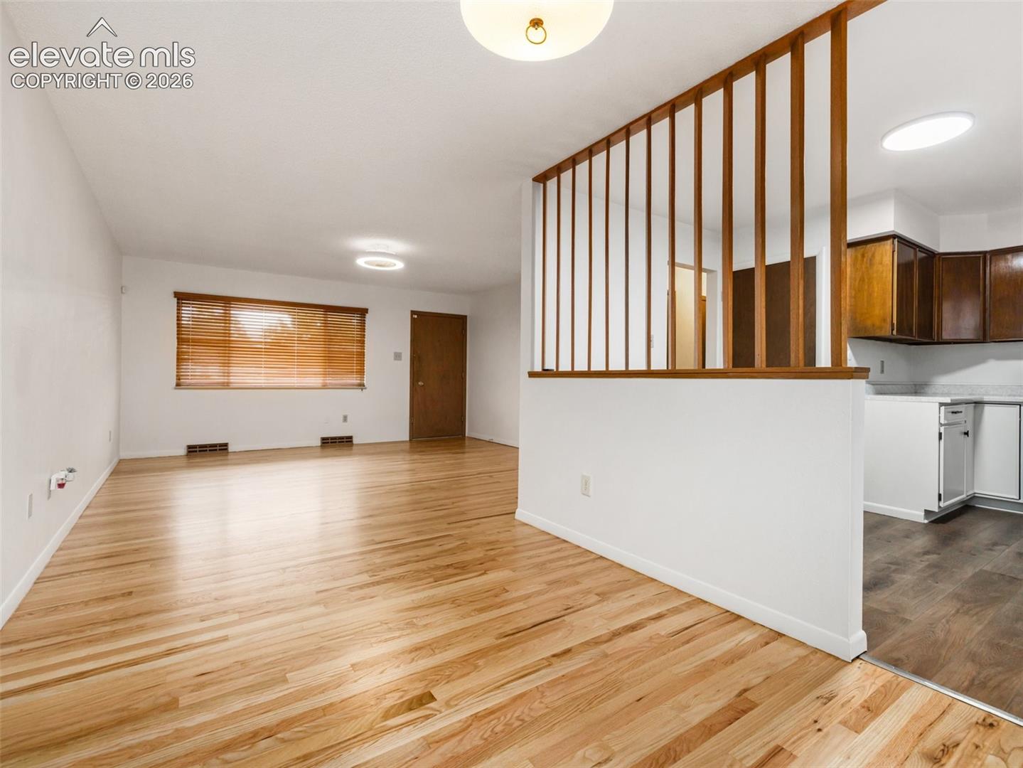 Hardwood flooring, wood slat partition, white walls, overhead lighting, kitchen with wood cabinetry