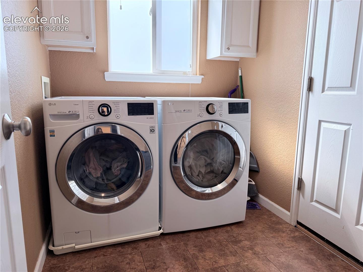 Laundry area featuring a window, overhead cabinetry, and wood-finish flooring