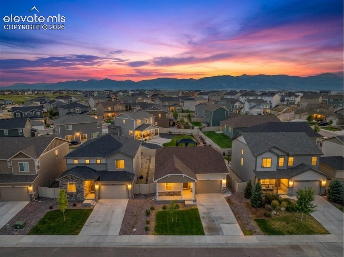 Residential neighborhood with varied architectural styles, individual garages, and mountain ranges in the distance