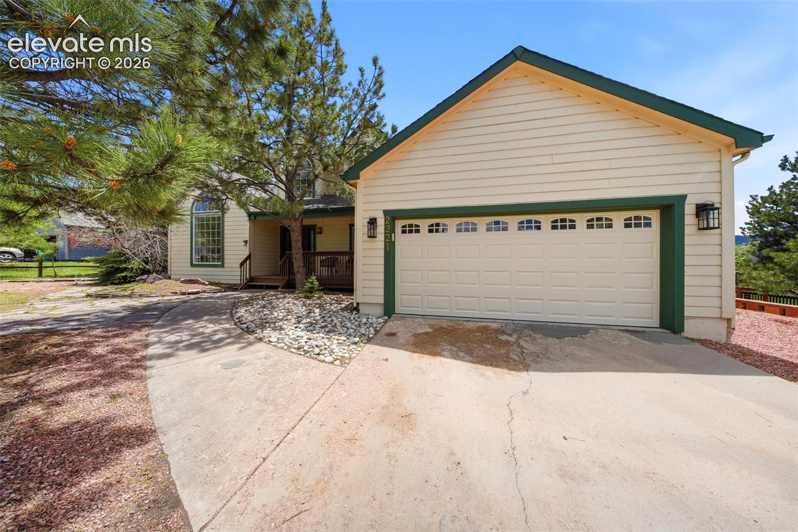 Light-colored siding exterior with dark green trim and a two-car garage