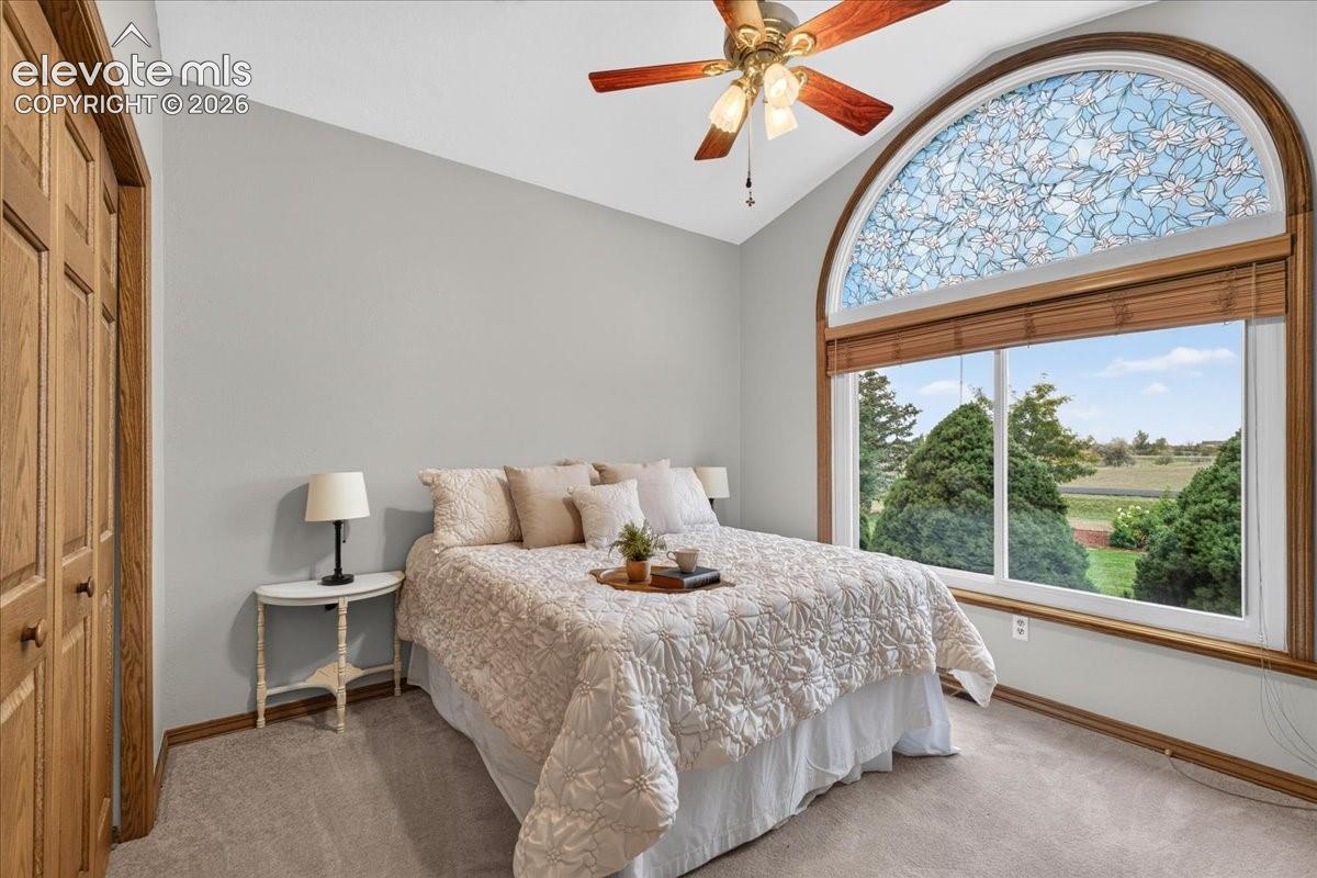Vaulted ceiling featuring a ceiling fan with light fixture, decorative arched transom window with floral detailing, sliding glass window, and wood-finish door trim