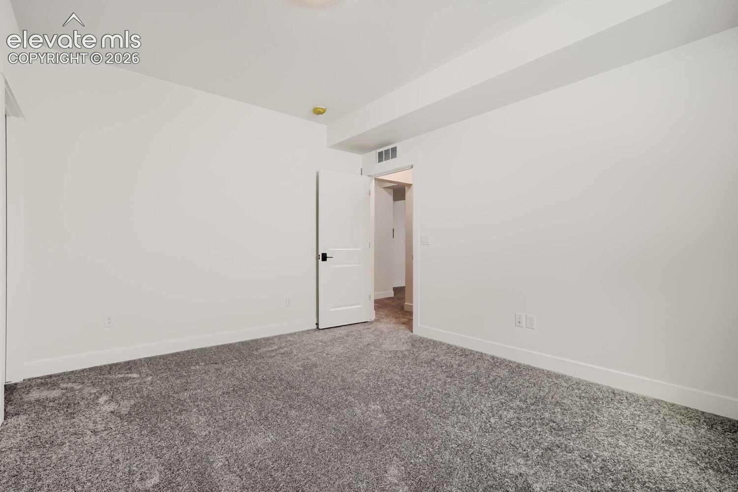 Spacious bedroom featuring neutral walls, a coffered ceiling with recessed lighting, and textured carpet flooring