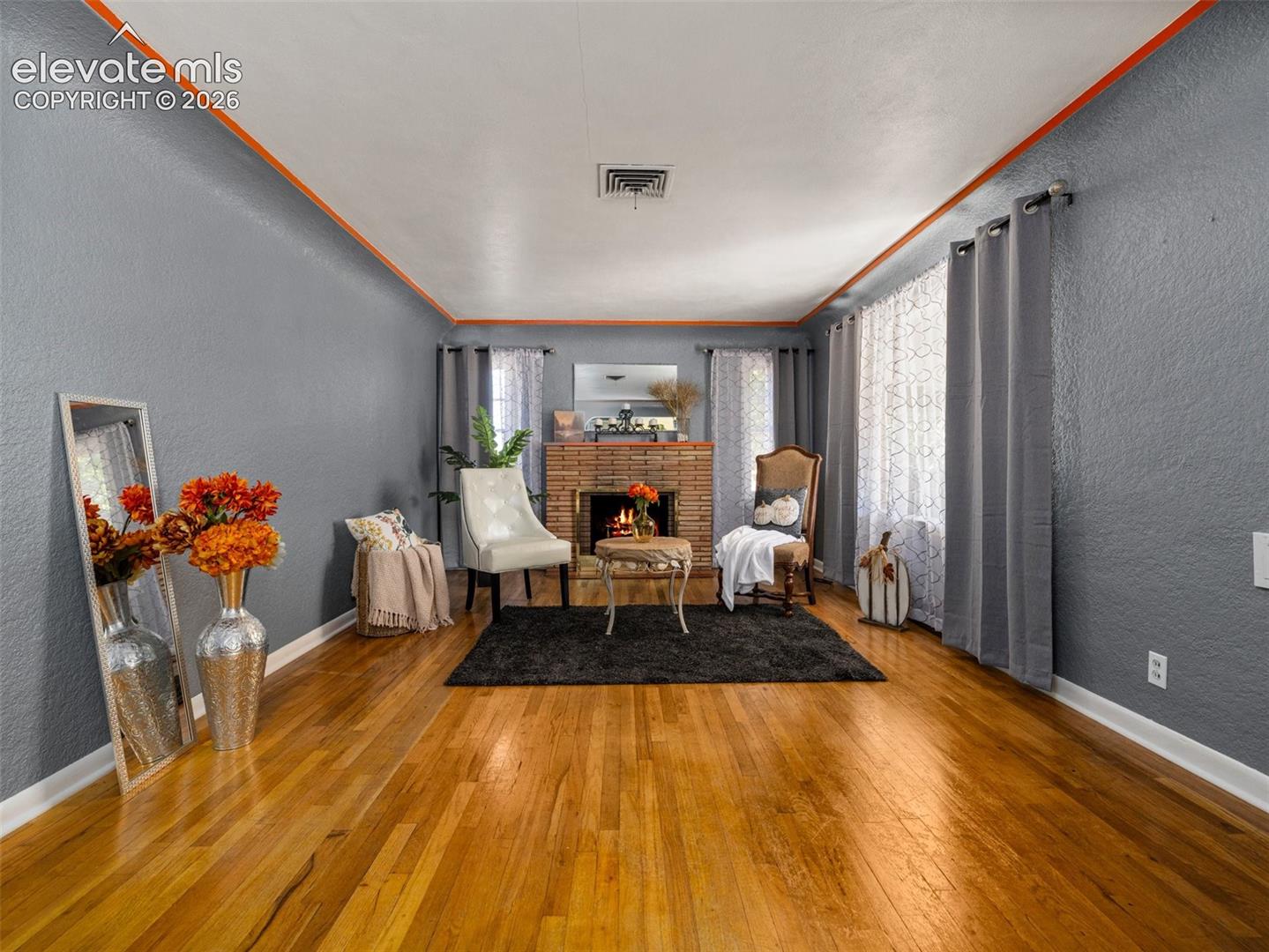 Living area featuring wood-finish flooring, a brick fireplace, and dual windows