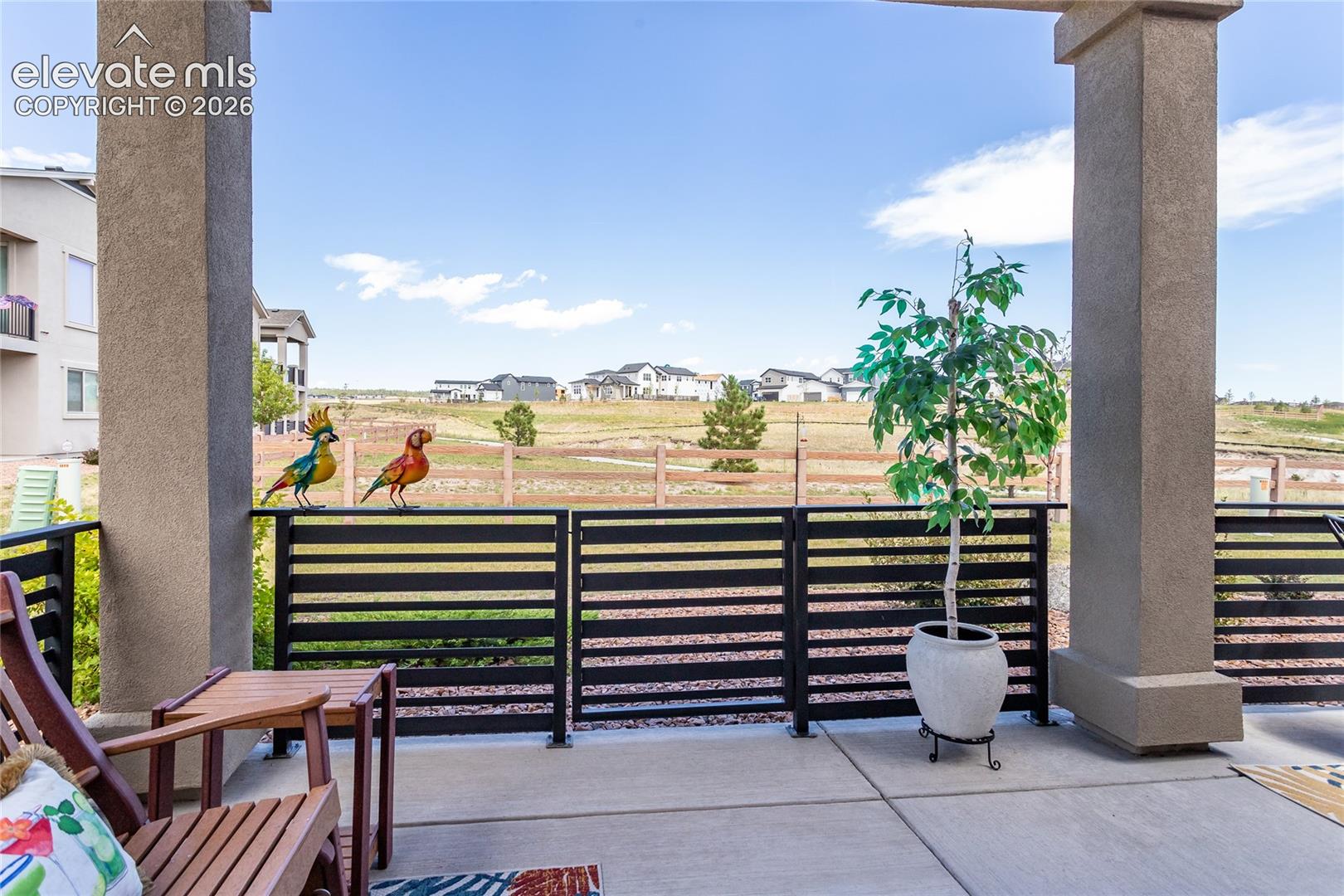 Expansive covered patio with concrete flooring framed by two substantial concrete columns, offering panoramic vistas of open landscape