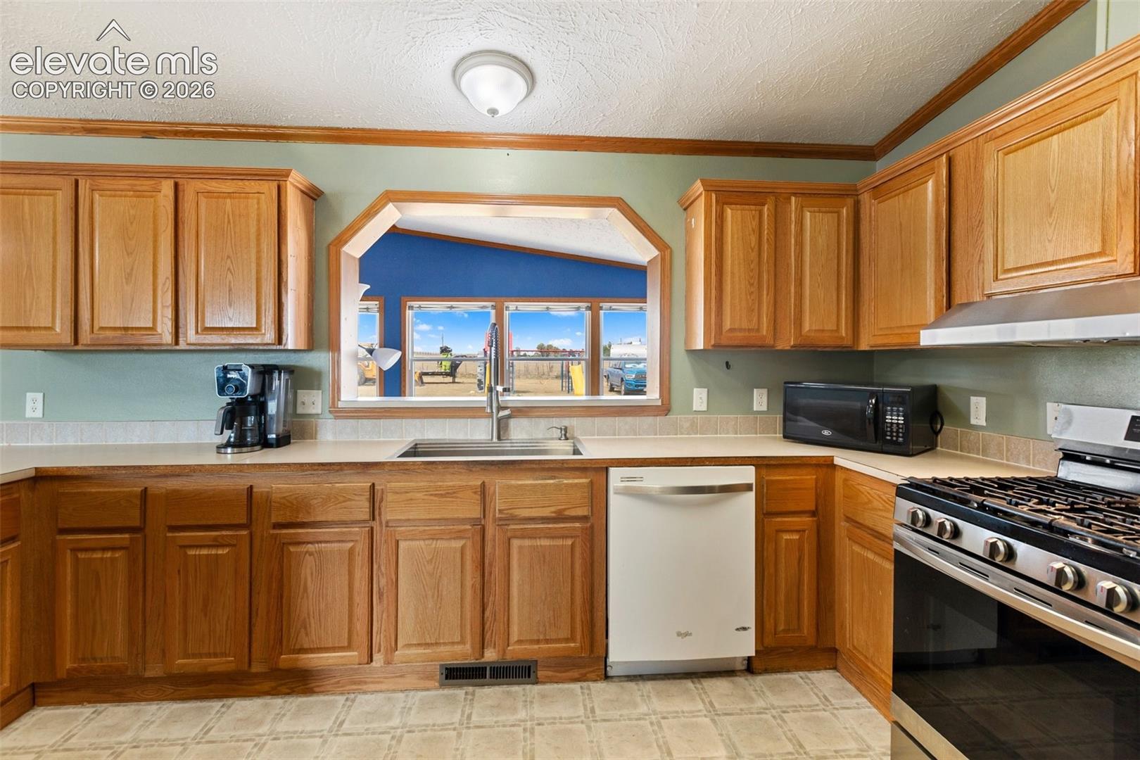 Kitchen featuring wood cabinetry, light countertops, a stainless steel gas range, and a built-in dishwasher