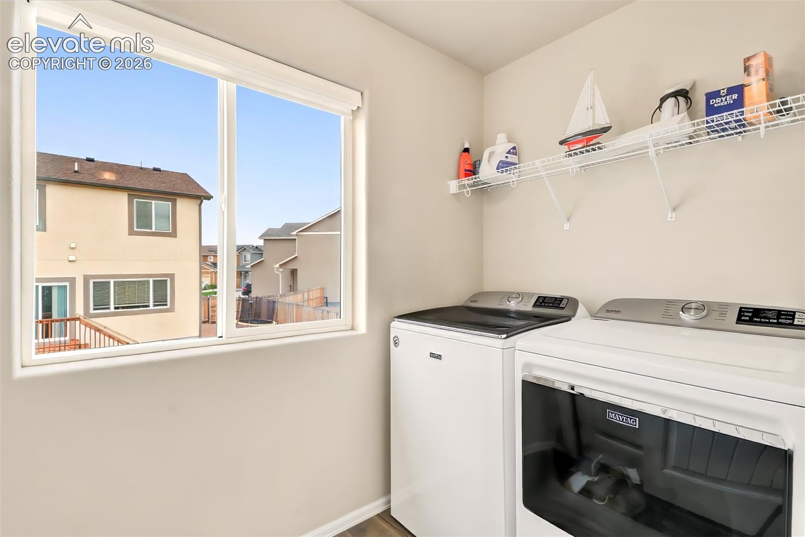 Laundry room featuring a large sliding window, wire shelving, and wood-finish flooring