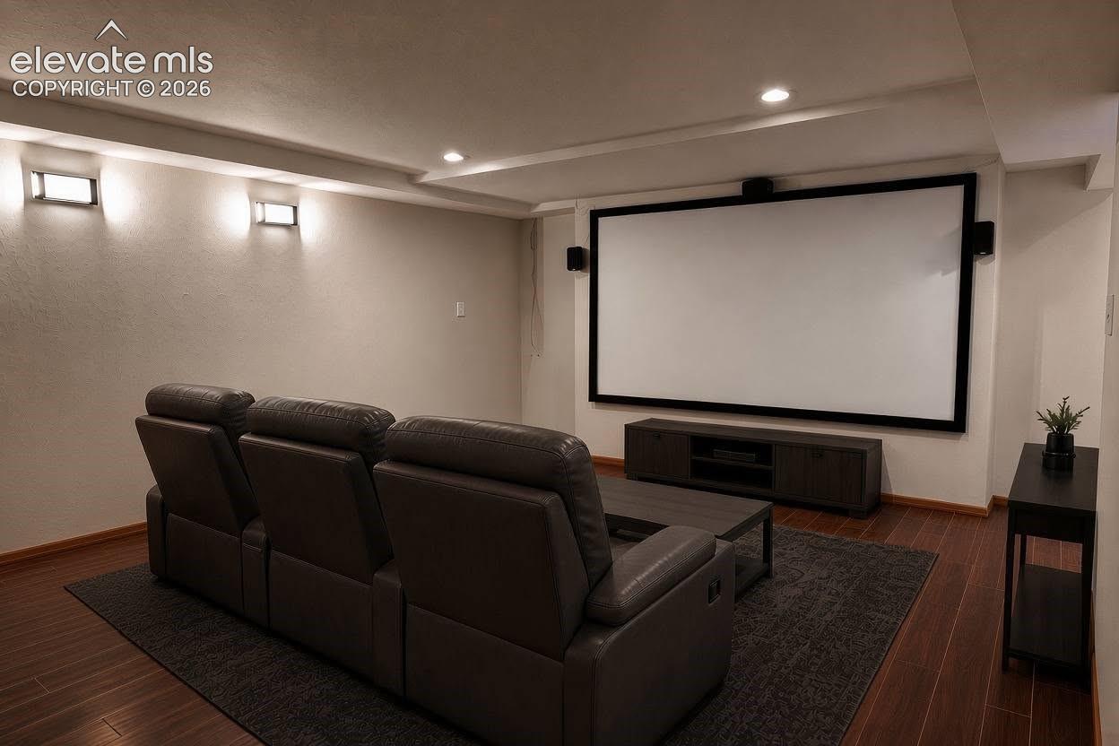 Media room featuring recessed lighting, wall-mounted light fixtures, wood-finish flooring, and a large projection screen, virtually steged 