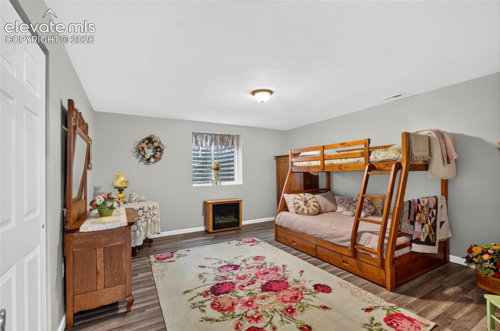 Wood-finish flooring, light gray walls, and a recessed window with blinds